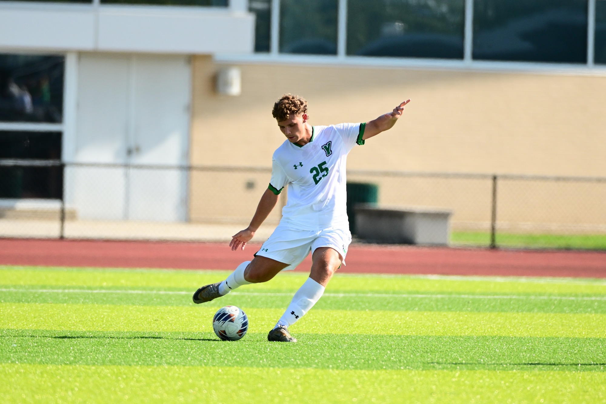 Male in white uniform kicking soccer ball
