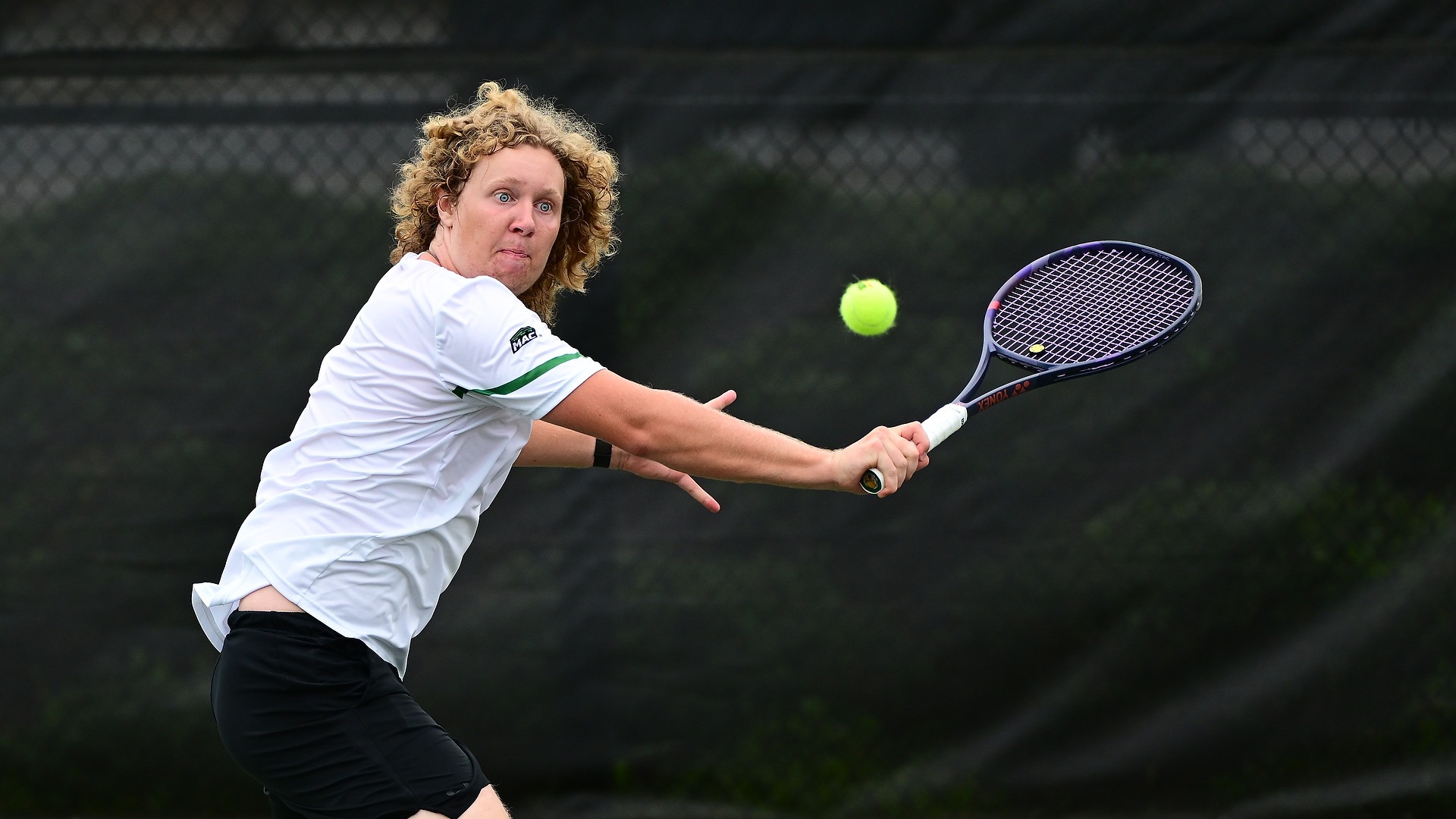 male tennis player attempts a backhand shot