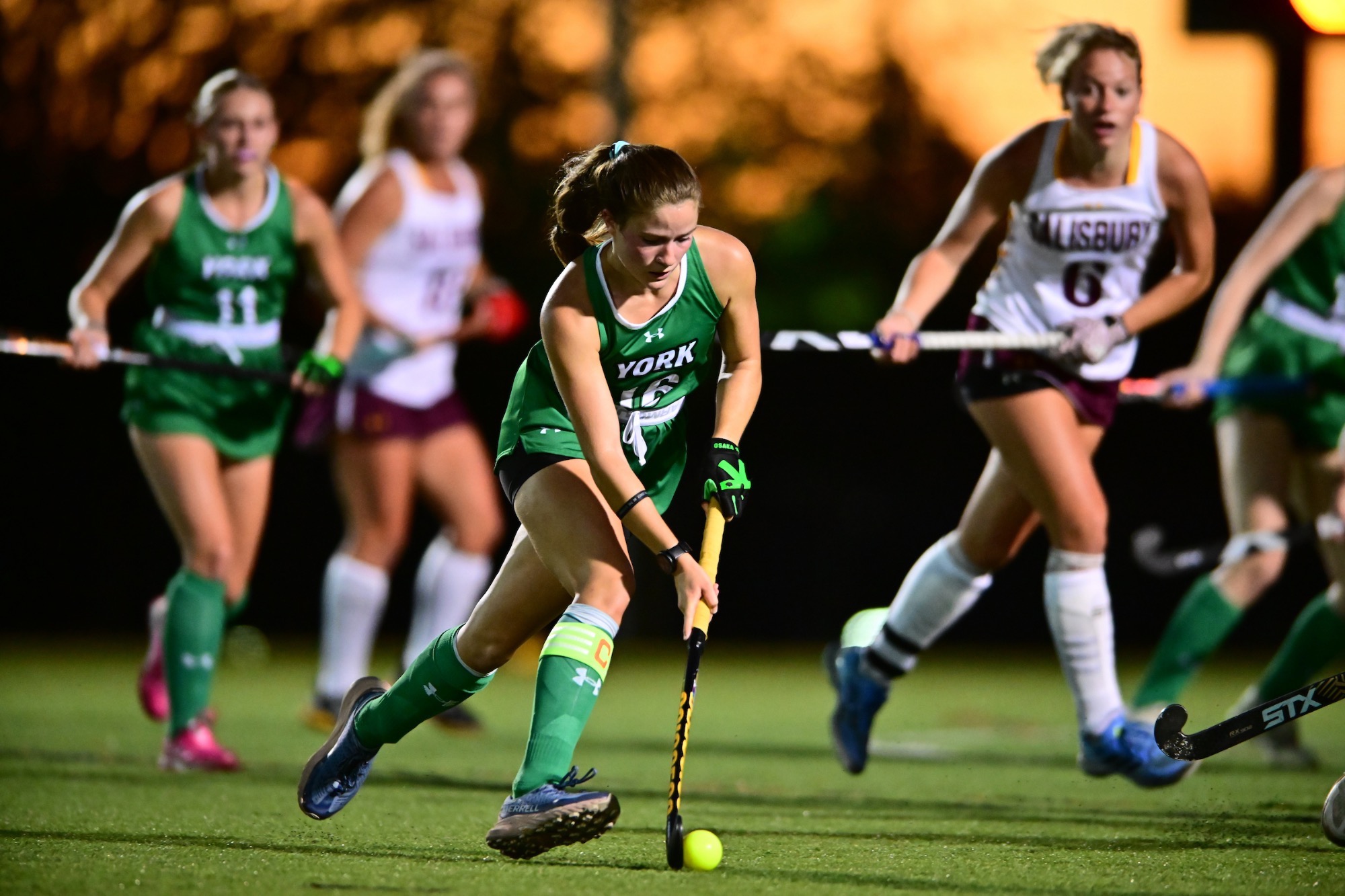 Female running with field hockey stick