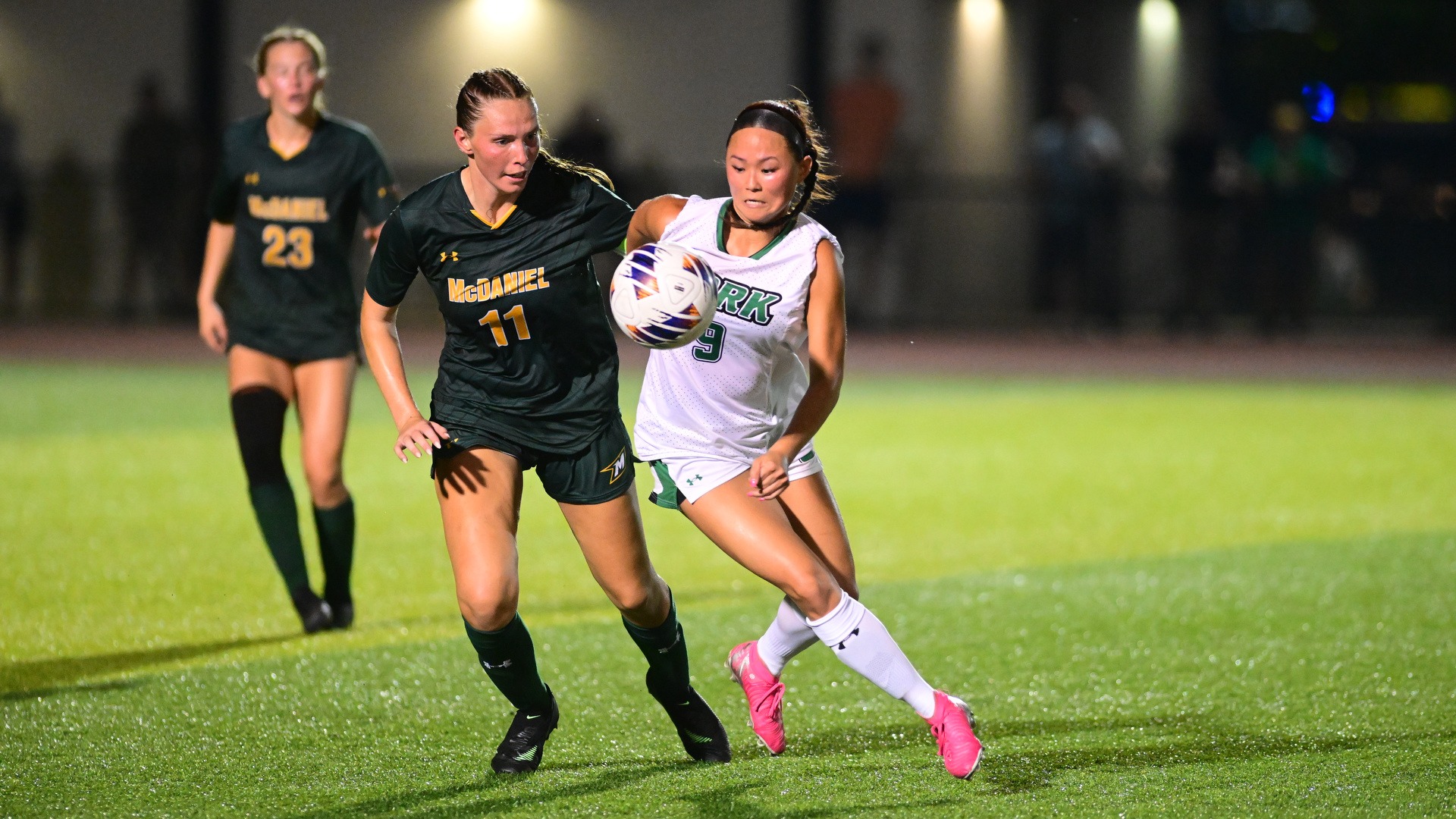 two female soccer players battle for the ball