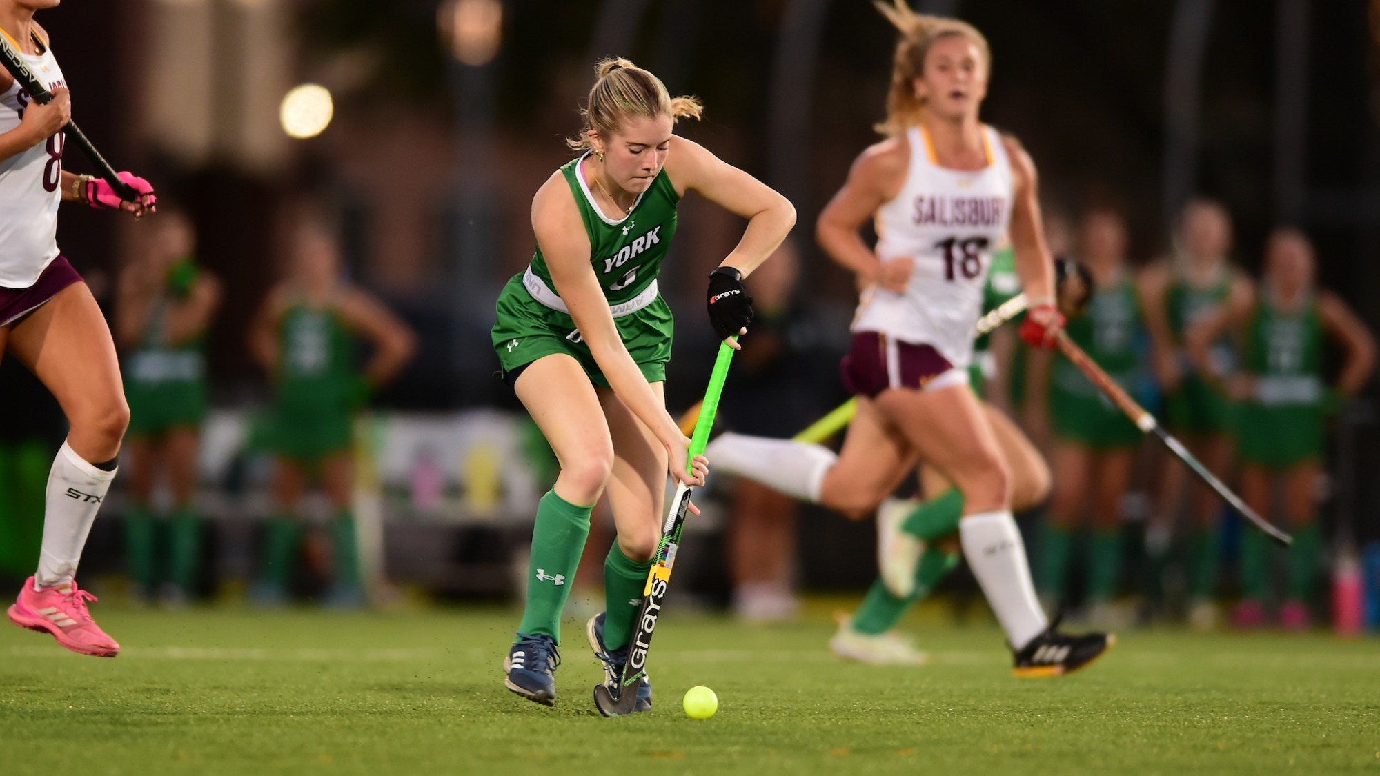 Female field hockey player dribbles ball down the field