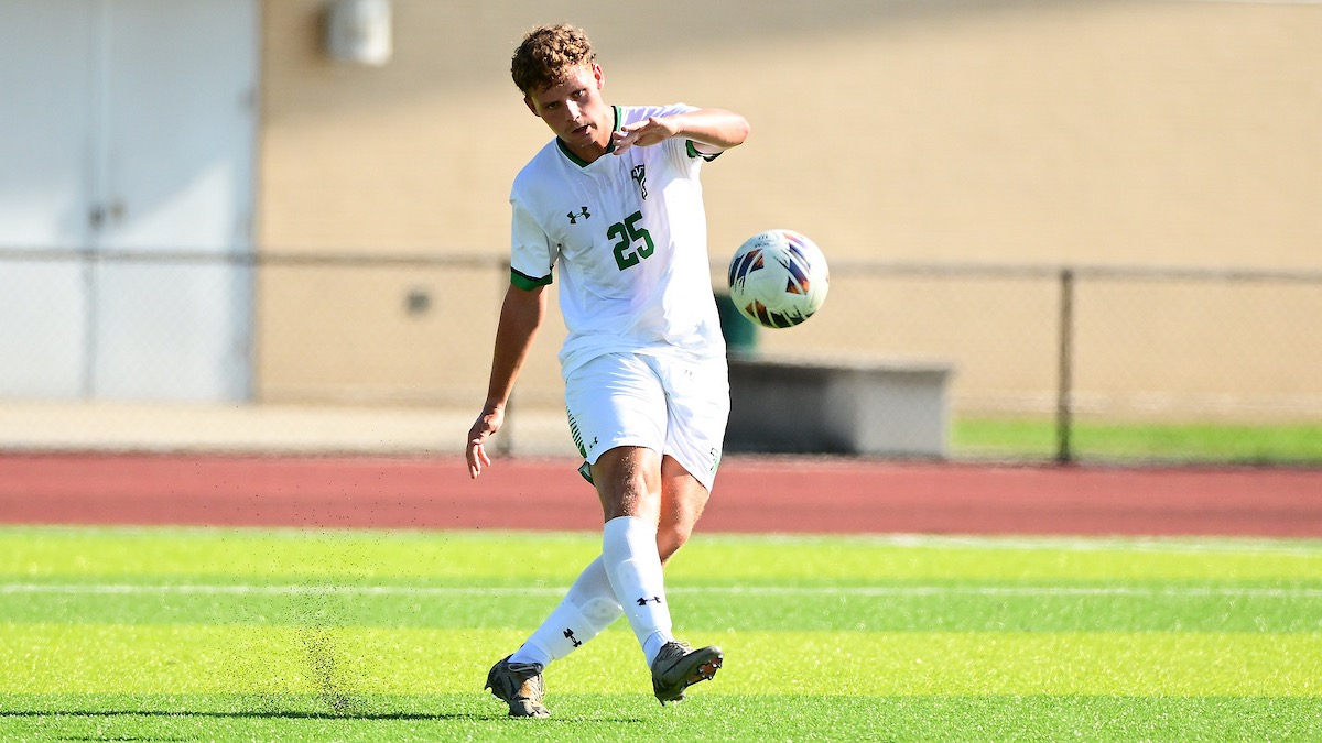 Male in white uniform kicking soccer ball