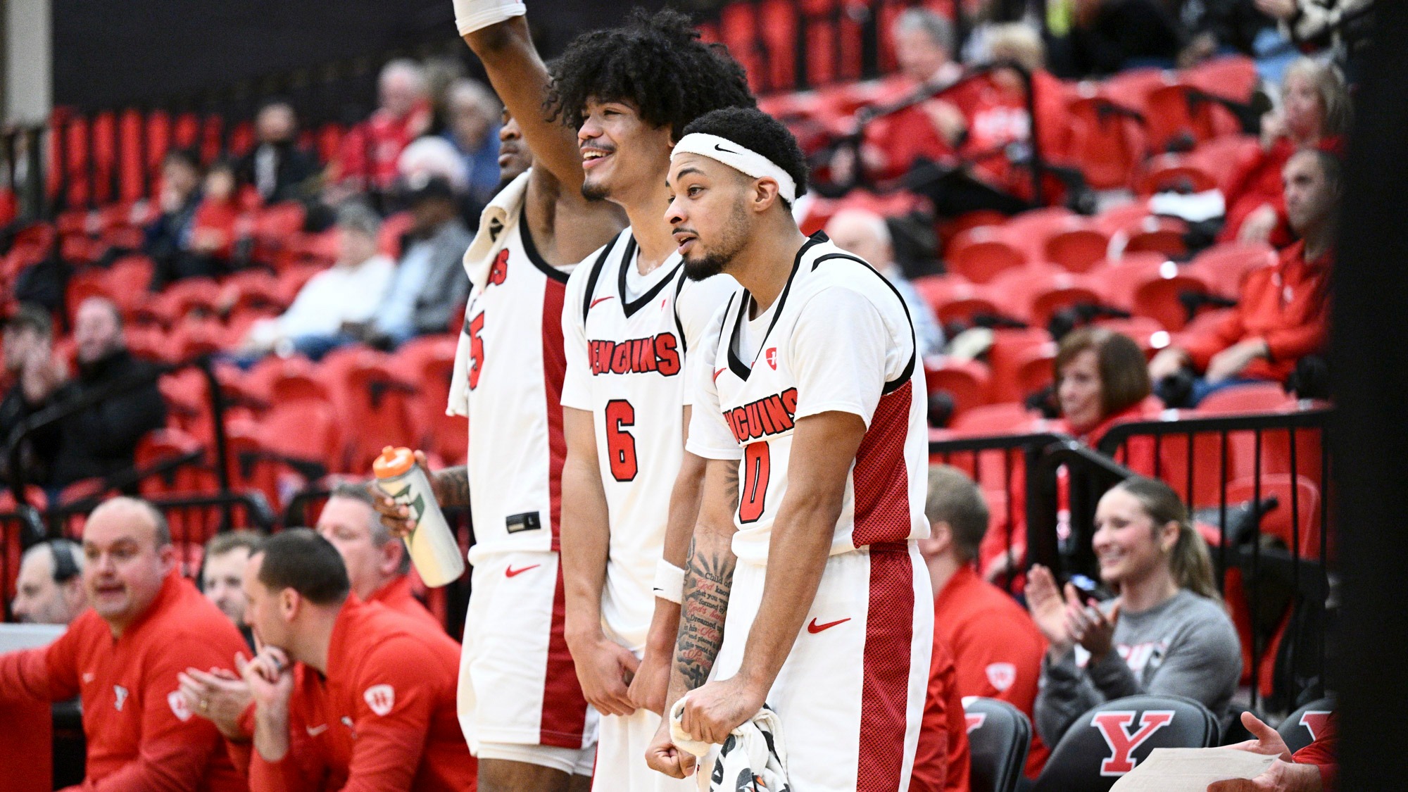 Three Penguins celebrate on the bench as Youngstown State's men's basketball team beat Thiel 103-52 on Dec. 14, 2025.