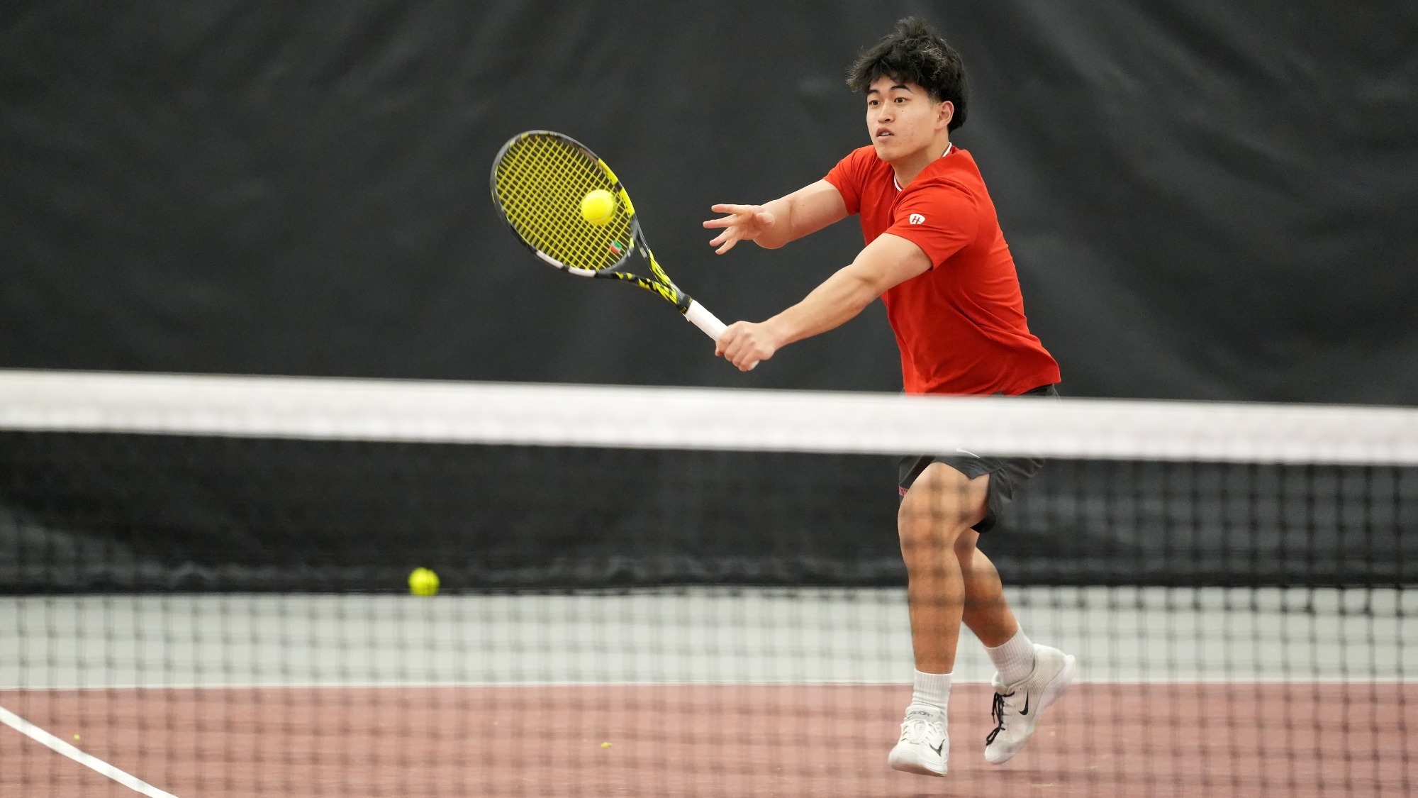 Takamasa Mishiro hits a tennis ball with a racquet