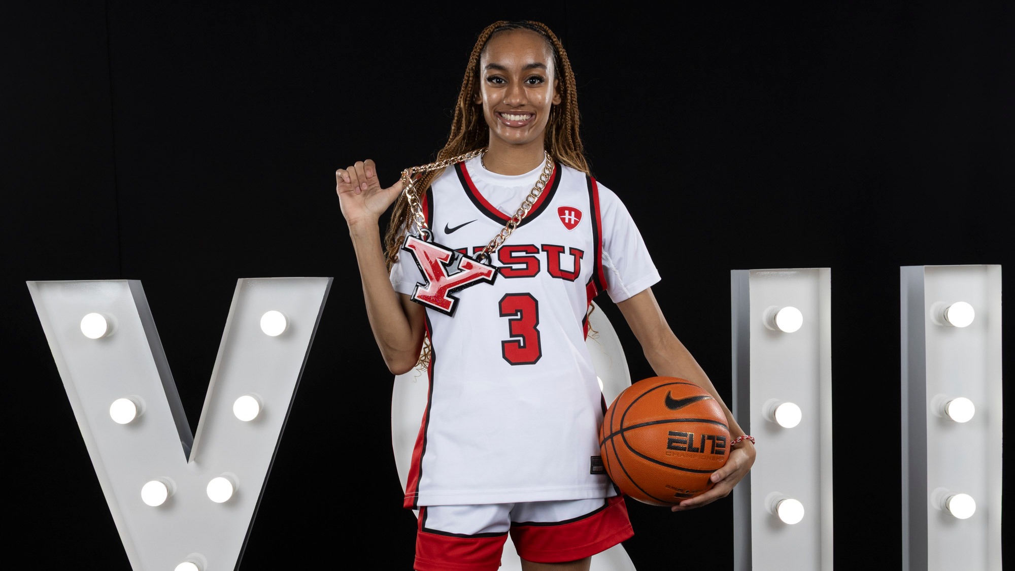 Jada Leonard in a photo studio setting holding a basketball and a chain around her neck with Youngstown State's Y logo