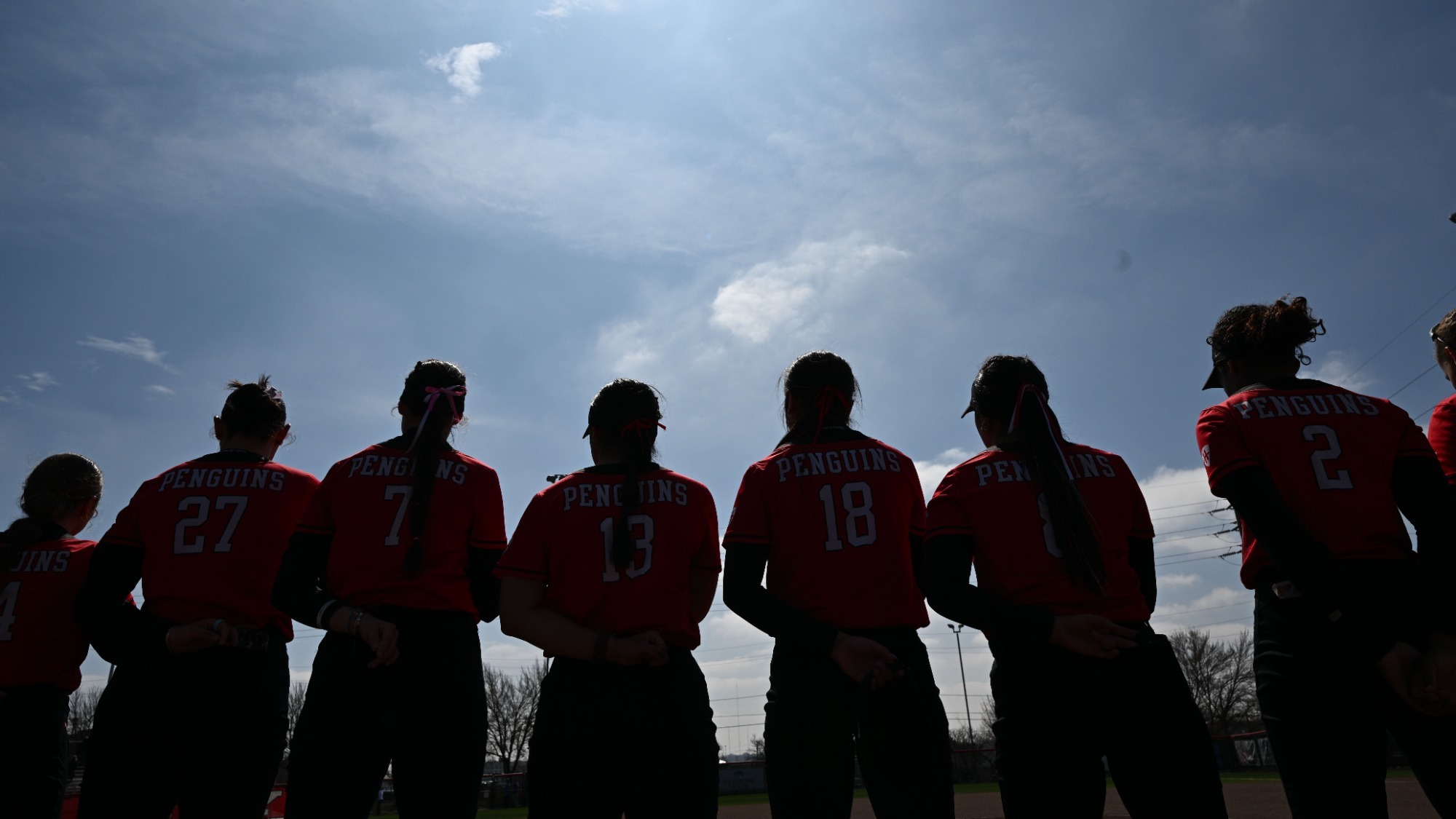 The Youngstown State softball team lines up along the third-base line for the playing of National Anthem