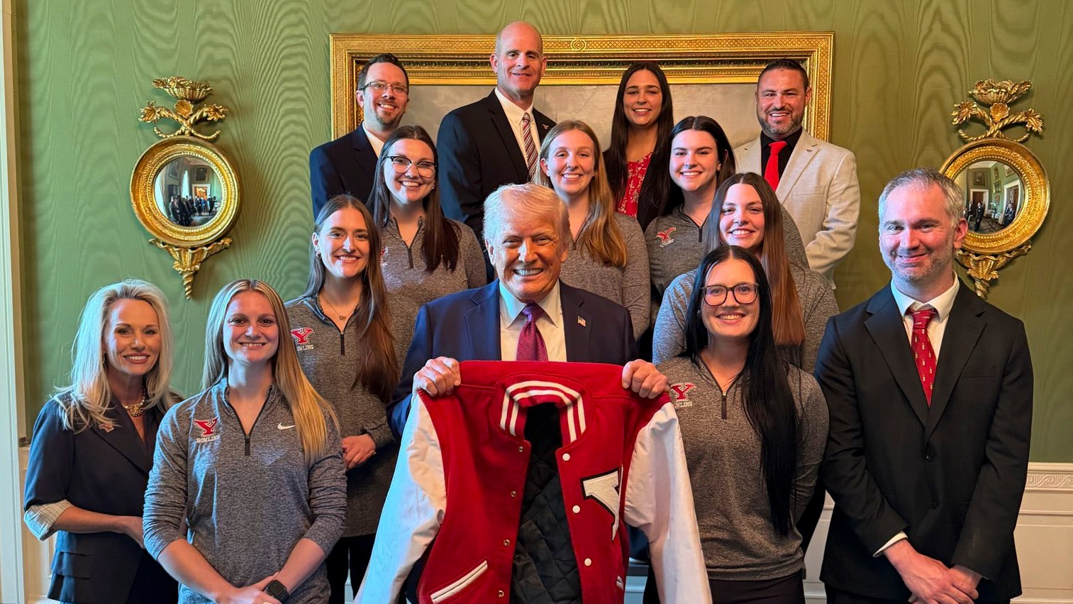 The Youngstown State bowling team and support staff stand around President Donald Trump in the Green Room of the White House. The President holds a YSU Letterman's jacket that was presented by the team. Photo by Margo Martin.