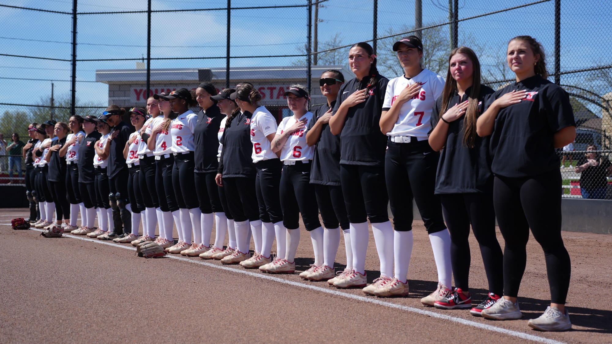 Members of the 2026 YSU Softball Team lineup along the third-base line for the National Anthem