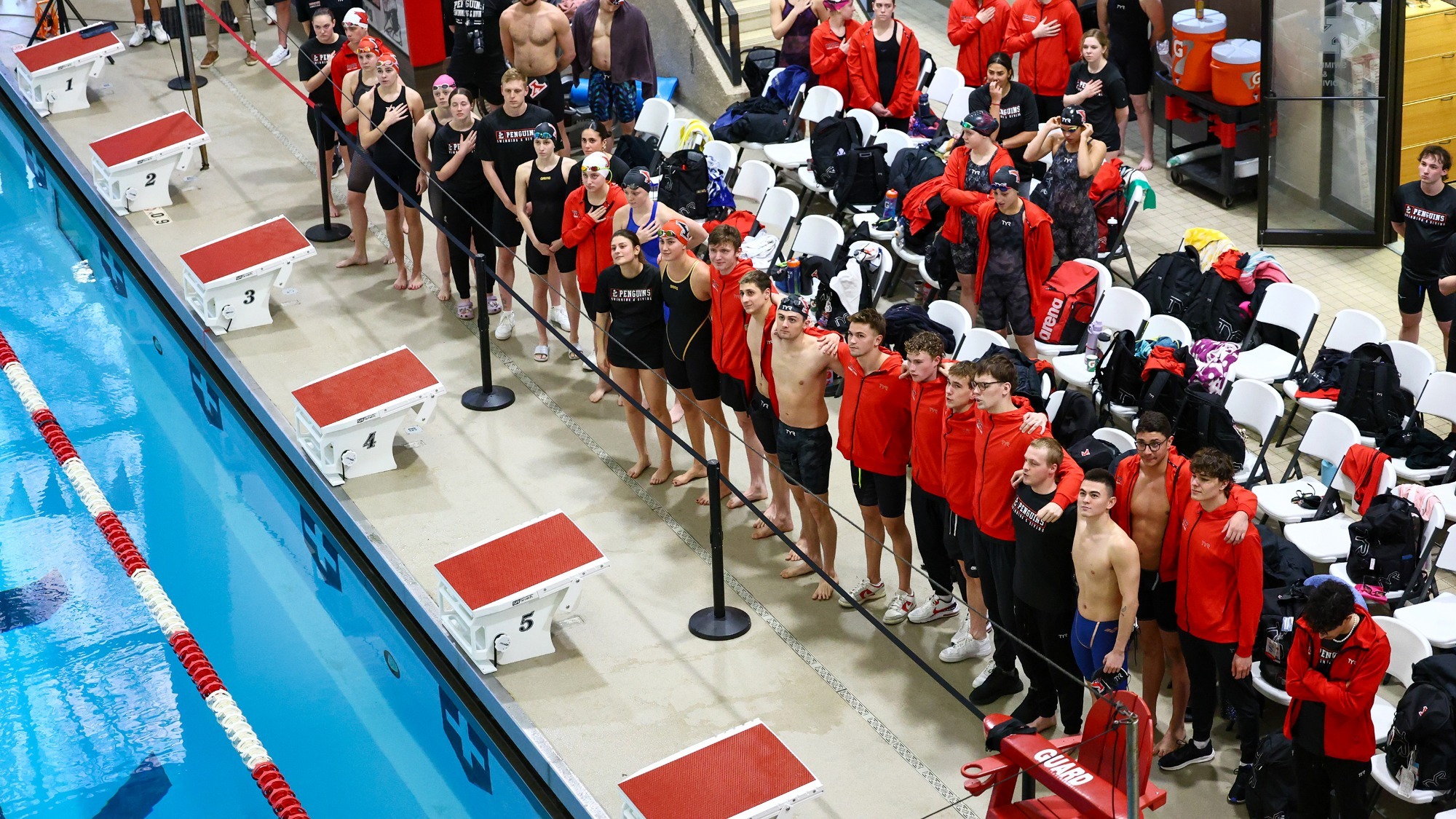 YSU Men's and Women's Swimming and Diving stands on the pool deck during the National Anthem.